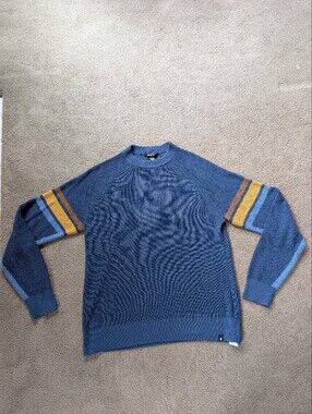 cotopaxi blue crewneck sweater with yellow and brown sleeve stripes